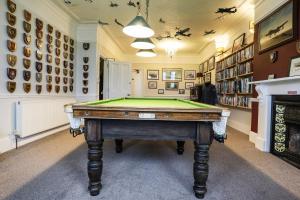 a room with a pool table in front of a fireplace at Lord Kitcheners Guest House in Lowestoft