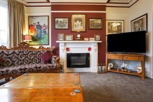 a living room with a television and a fireplace at Lord Kitcheners Guest House in Lowestoft