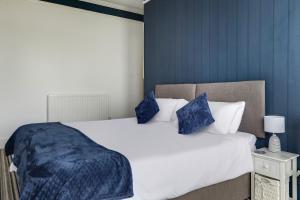 a bedroom with a large white bed with blue pillows at Lord Kitcheners Guest House in Lowestoft
