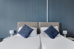 two beds with blue pillows sitting next to each other at Lord Kitcheners Guest House in Lowestoft