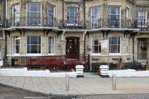 a building with a red fence in front of it at Lord Kitcheners Guest House in Lowestoft