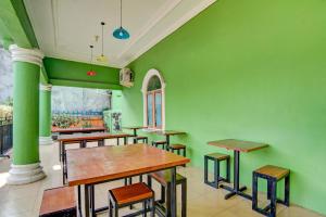 a restaurant with green walls and wooden tables and stools at OYO 92497 Penginapan Pasir Indah SyariahNearMonument Park City Sand Pengaraian in Pasirpengarayan