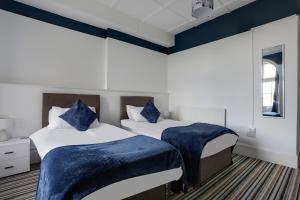 two beds in a room with blue and white walls at Lord Kitcheners Guest House in Lowestoft
