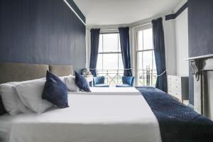 a bedroom with a large white bed with blue pillows at Lord Kitcheners Guest House in Lowestoft +37 photos