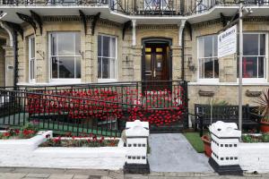 a house with red flowers in front of it at Lord Kitcheners Guest House in Lowestoft