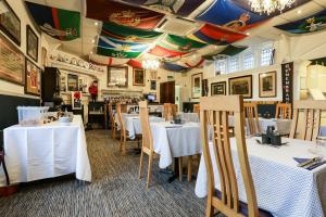 a restaurant with white tables and chairs and a ceiling at Lord Kitcheners Guest House in Lowestoft
