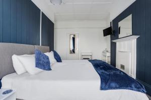 a bedroom with a white bed with blue accents at Lord Kitcheners Guest House in Lowestoft