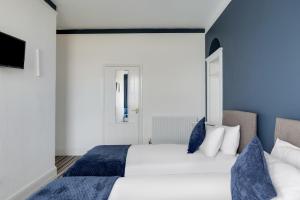 a bedroom with a large white bed with blue pillows at Lord Kitcheners Guest House in Lowestoft