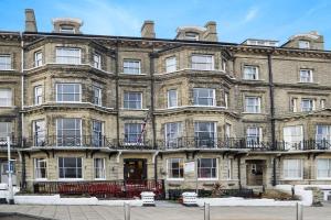 a large brick building with a flag in front of it at Lord Kitcheners Guest House in Lowestoft