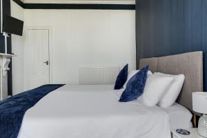 a bedroom with a white bed with blue pillows at Lord Kitcheners Guest House in Lowestoft