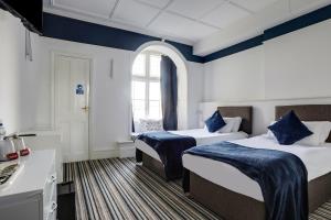 a hotel room with two beds and a window at Lord Kitcheners Guest House in Lowestoft