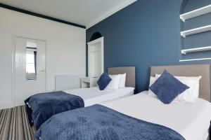 two beds in a room with blue walls at Lord Kitcheners Guest House in Lowestoft