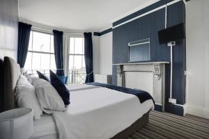 a bedroom with a large white bed and a fireplace at Lord Kitcheners Guest House in Lowestoft