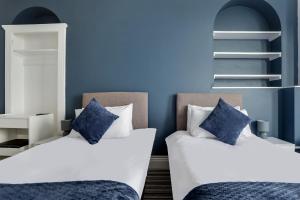 two beds and a couch in a room with blue walls at Lord Kitcheners Guest House in Lowestoft