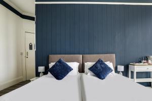 two beds with blue pillows in a bedroom at Lord Kitcheners Guest House in Lowestoft