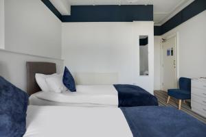 a bedroom with two beds and a blue chair at Lord Kitcheners Guest House in Lowestoft