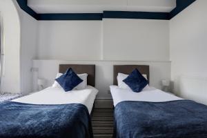 two beds in a room with blue pillows on them at Lord Kitcheners Guest House in Lowestoft
