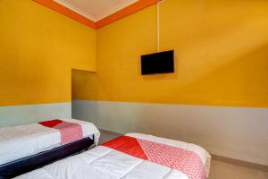 a room with two beds and a tv on the wall at Hotel O Wisma Sakinah Syariah in Rambah