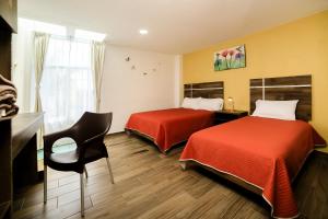 a hotel room with two beds and a chair at Capital O Hotel Boutique Las Torres in Tlaxcala de Xicohténcatl