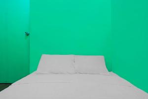 - un lit blanc dans une chambre dotée d'un mur vert dans l'établissement Hotel O Joyoakis Homestay SyariahNearMall Nagoya Hill, à Nagoya