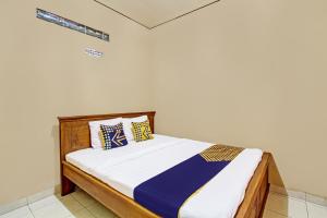 a bed with blue and yellow pillows in a room at Hotel O Timoti Guest House in Potrojayan