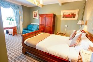 a bedroom with a bed and a blue chair at OYO Lamphey Hall Hotel in Pembroke