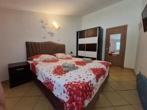 a bedroom with a bed with a red and white bedspread at Nina Apartment in Škaljari