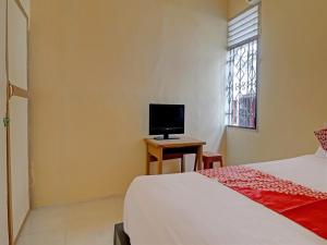 a bedroom with a bed and a television on a table at Hotel O Excellent Kost in Jambi