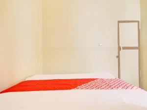 a white bed with a red blanket on it at Hotel O Excellent Kost in Jambi +21 photos