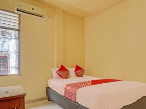 a bedroom with a bed with red pillows at Hotel O Excellent Kost in Jambi