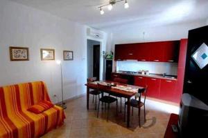 a living room with a table and a kitchen with red cabinets at Poggio Degli Olivi in Saturnia