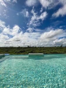 a pool of water with a blue sky and clouds at Pousada La Grécia in Camocim +5 photos