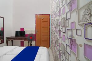 a bedroom with a bed and a wall with pictures at Hotel O Putri Guest House Syariah Near SPBU Rimbo Panjang in Pekanbaru