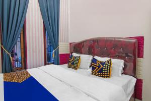 a bed with a red headboard and pillows on it at Hotel O Putri Guest House Syariah Near SPBU Rimbo Panjang in Pekanbaru +18 photos