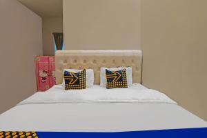 a bed with two pillows on it with a white bed at Hotel O Putri Guest House Syariah Near SPBU Rimbo Panjang in Pekanbaru