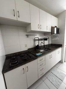 a kitchen with white cabinets and a black counter top at Smart Apê! in Porto Velho +3 photos