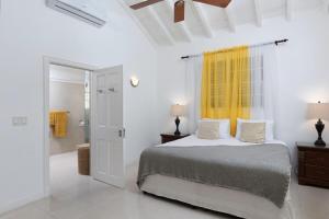 ein weißes Schlafzimmer mit einem Bett und einem gelben Vorhang in der Unterkunft Refreshing 2bed Townhome walking distance to beach in Saint James + 18 Fotos