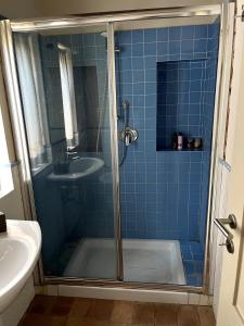 La salle de bains est pourvue de carrelage bleu, d'une douche et d'un lavabo. dans l'établissement Apartment in the countryside, à Cerreto Guidi