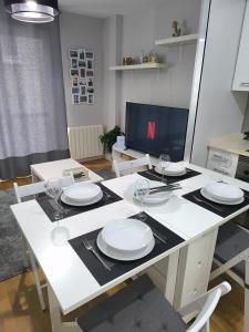 einen weißen Tisch mit Tellern und Weingläsern darauf in der Unterkunft El Piso de Montse in A Coruña