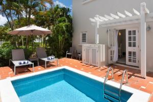 einem Pool mit Stühlen und einem Sonnenschirm neben einem Haus in der Unterkunft Refreshing 2bed Townhome walking distance to beach in Saint James