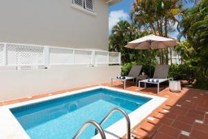 ein Swimmingpool mit zwei Stühlen und einem Sonnenschirm in der Unterkunft Refreshing 2bed Townhome walking distance to beach in Saint James