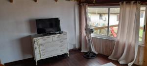 a tv on a dresser in a room with a window at La Ruca in Punta Del Diablo
