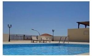 a swimming pool with two chairs next to a building at Park View Gardens H502 in Peyia