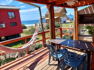 a deck with a hammock and a table and chairs at La Ruca in Punta Del Diablo