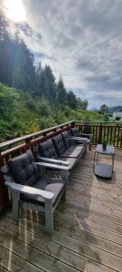 a row of benches sitting on top of a wooden deck at Apartment- fjord view, big terrace, close to Moa in Ålesund