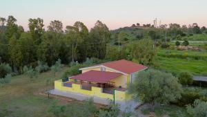 a small yellow house with a red roof in a field at Villa Scirocco in Cala Liberotto