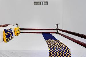 Hotel O Umi Homestay Syariah في سيدوارجو: سرير مع وسائد النقط الصفراء و الزرقاء