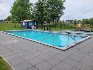 a swimming pool with a house in a park at Holiday Home Garden View in Tzummarum