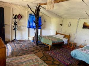 a room with two beds and a tree in it at Authentic Mara Bush Home in Sekenani