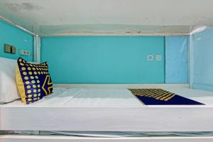 a bed in a room with a blue wall at Hotel O Lobak Hostel CapsuleNearAyam Goreng Terowongan in Alastuwo